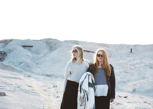 Two girls with sunglasses standing in a sand dune with vegan, reef safe face blue and orange sunscreen on their noses